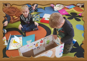 Dzieci ozdabiają pudełko swoimi rysunkami.